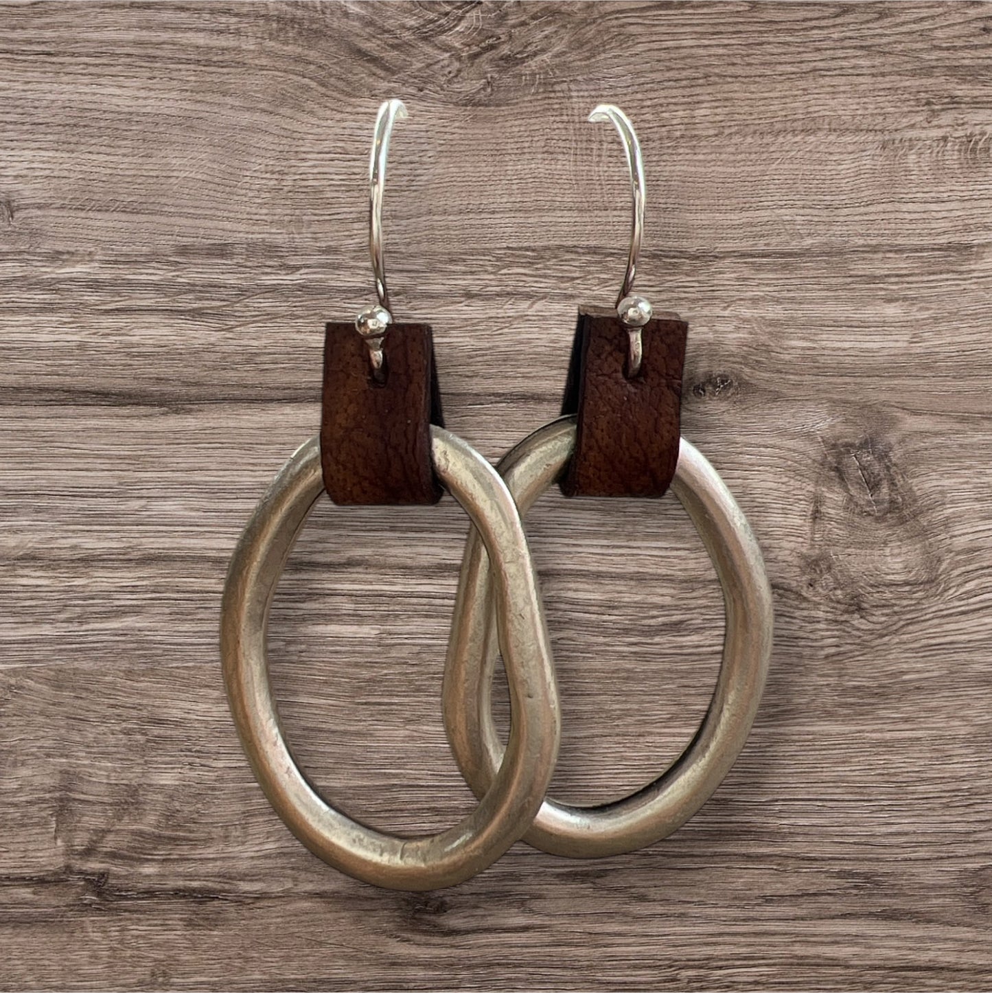 Leather and metal earrings with a sleek, modern design featuring a combination of textured leather and metallic accents.