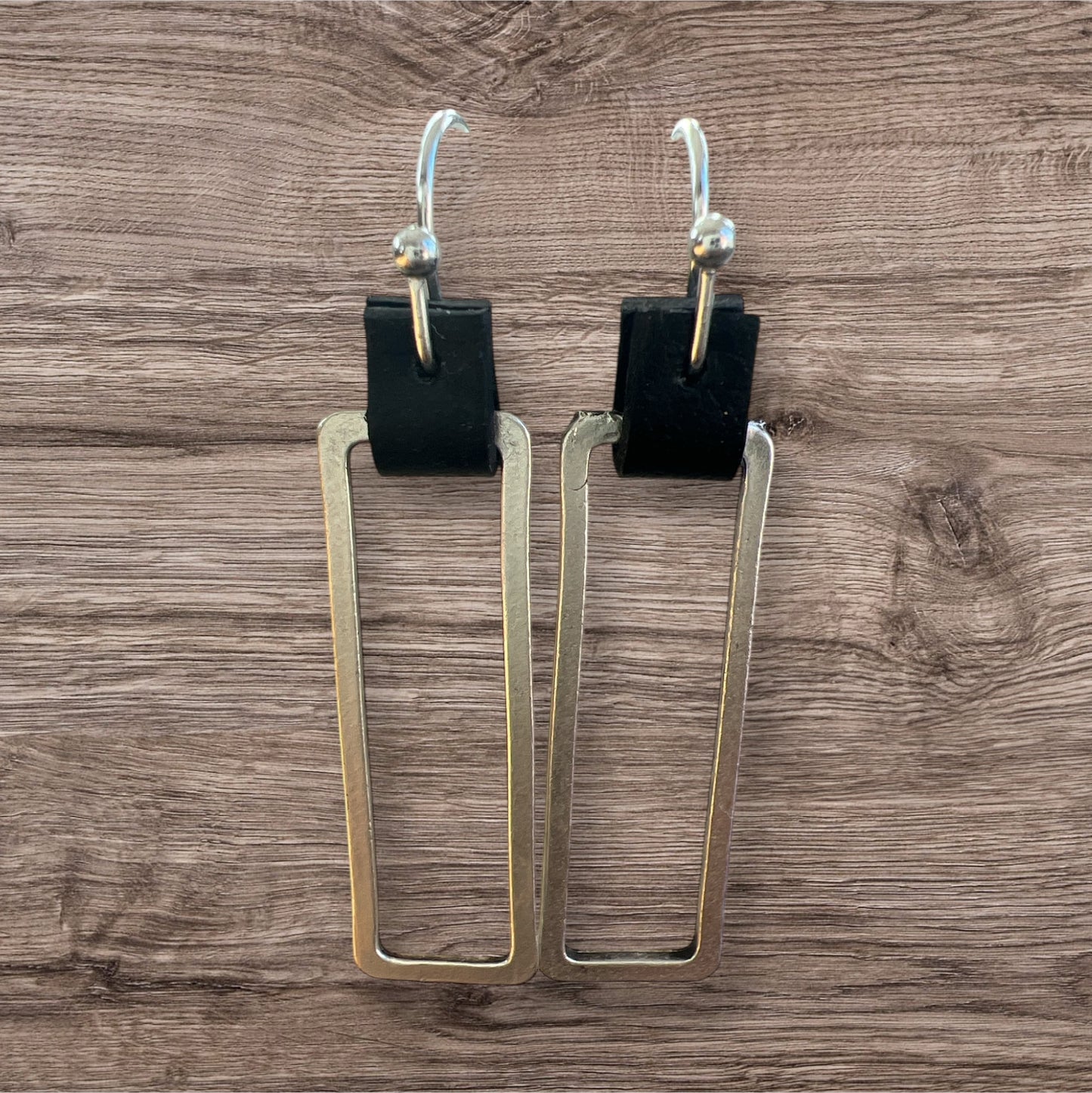 Leather and metal earrings with a sleek, modern design featuring a combination of textured leather and metallic accents.
