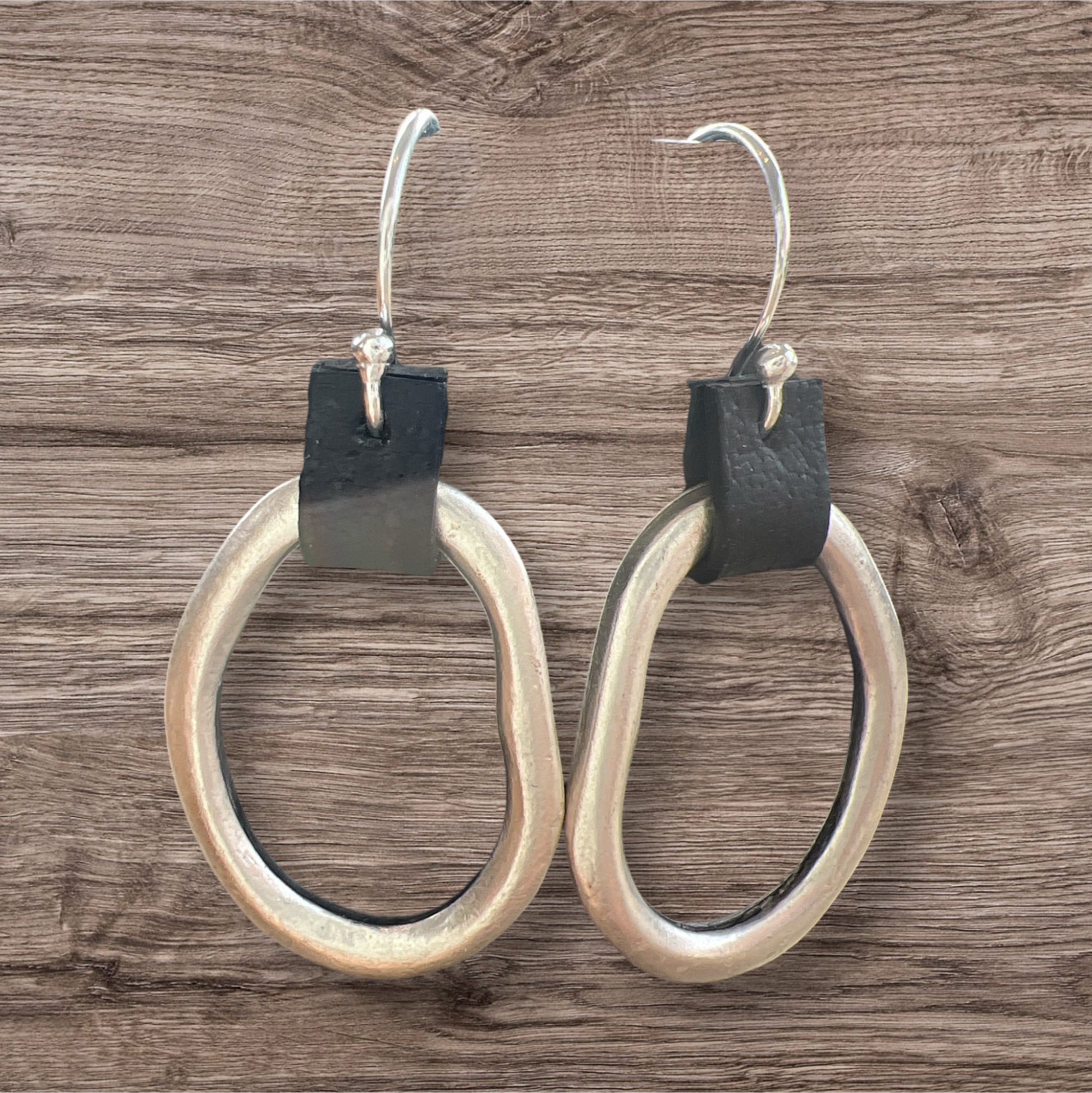 Leather and metal earrings with a sleek, modern design featuring a combination of textured leather and metallic accents.