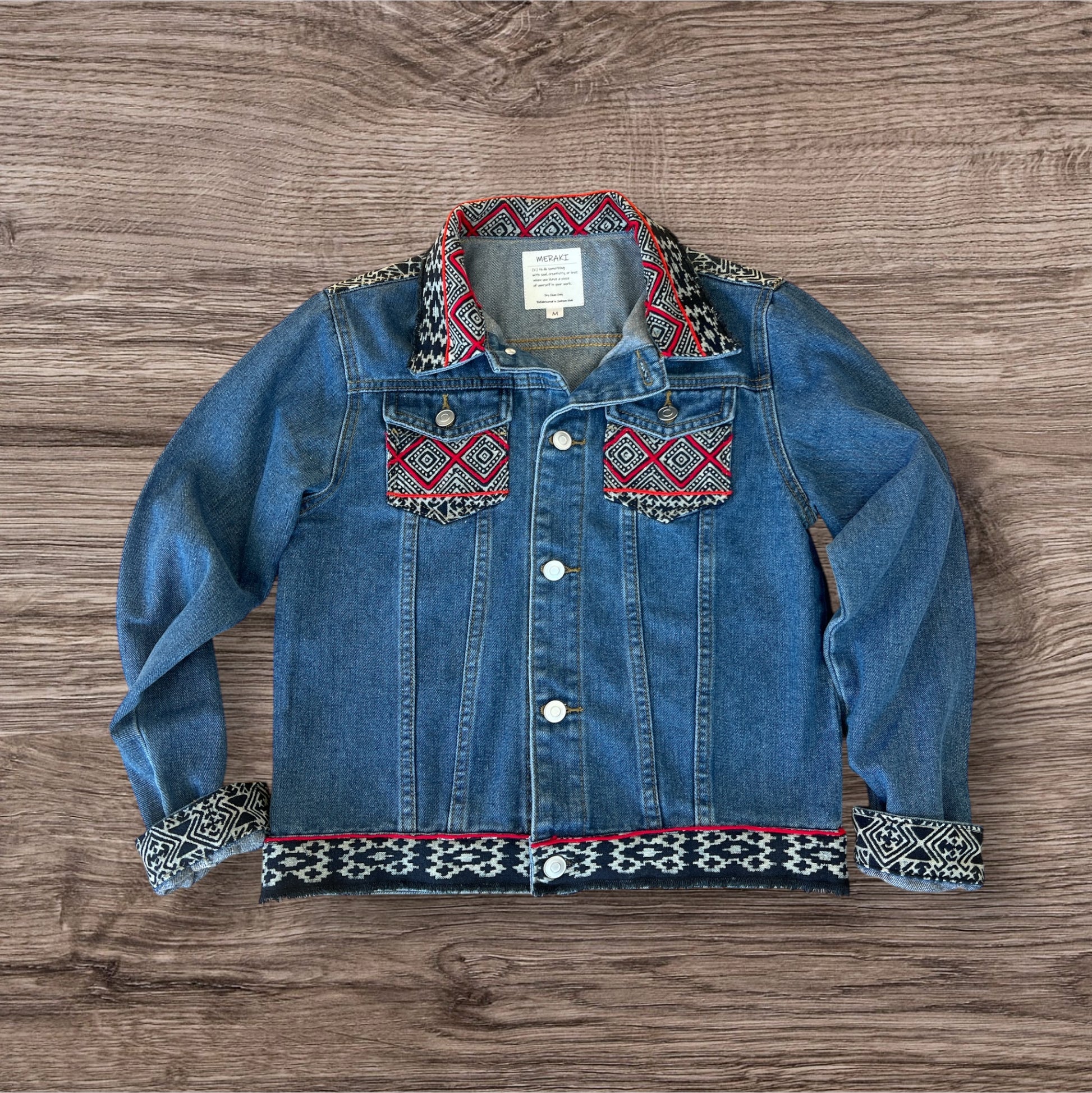 Jean jacket embellished with vibrant batik Hmong print textile, combining traditional patterns with a modern denim style