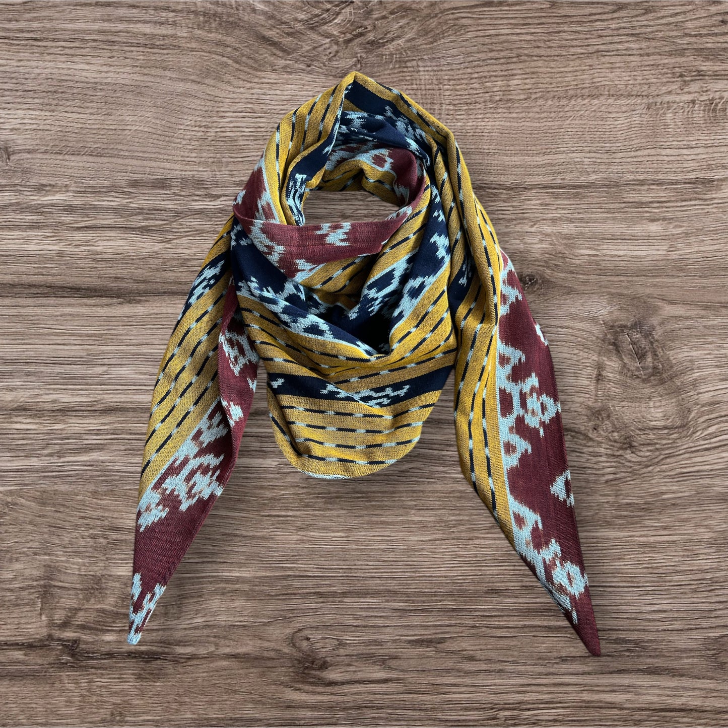 Elegant Ikat scarf with a colorful, intricate design in shades of yellow and brown, offering a unique accessory for any wardrobe