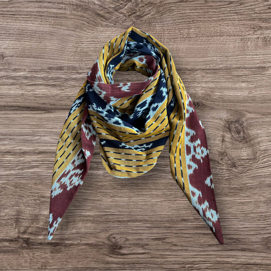 Elegant Ikat scarf with a colorful, intricate design in shades of yellow and brown, offering a unique accessory for any wardrobe